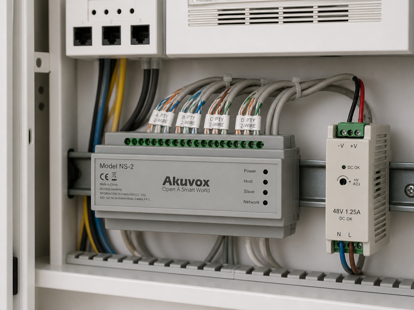 Akuvox NS-2 on a DIN rail in a comms cupboard with labelled 2-wire pairs