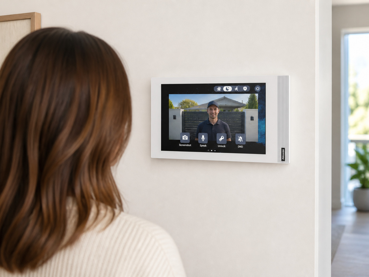 Resident answering a visitor on a wall-mounted Akuvox S562 white indoor monitor