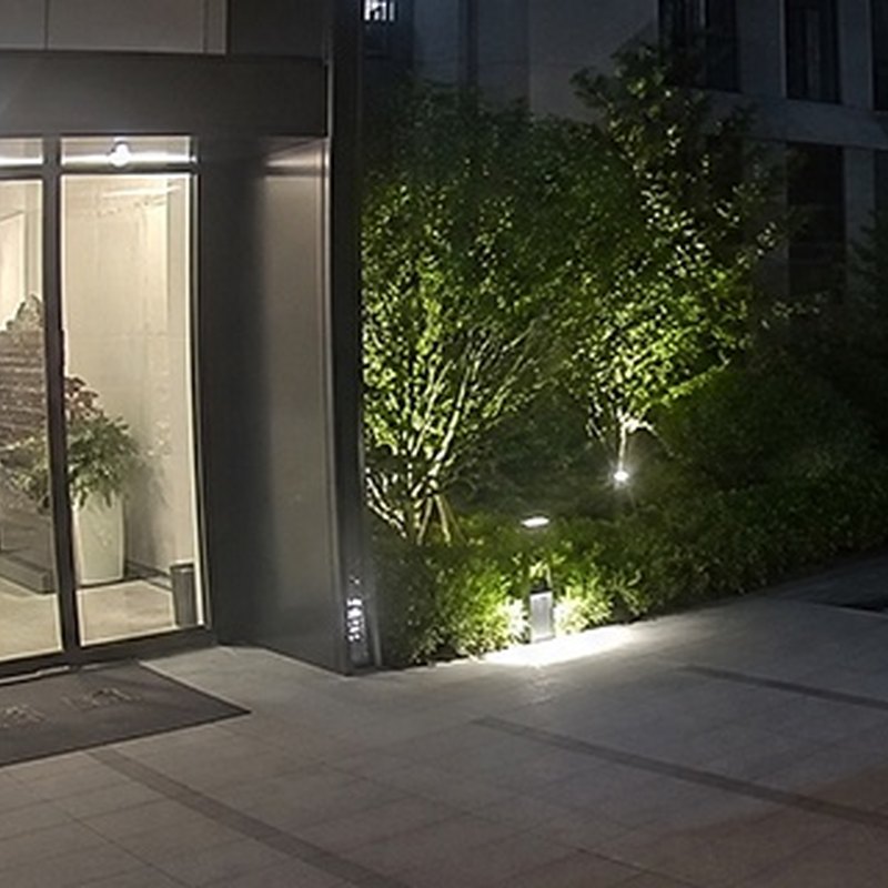 Night-time colour footage of a building entrance lit by the camera's white light